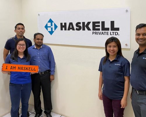 Singapore office employees posing with "I Am Haskell" sign
